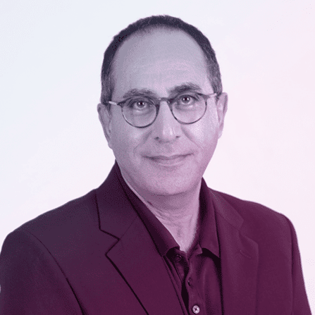 A middle-aged man with short dark hair and glasses is wearing a dark blazer and collared shirt, facing the camera with a neutral expression against a light background.